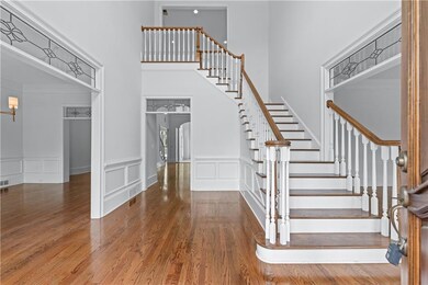 Staircase featuring a high ceiling, wood finished floors, a decorative wall, and wainscoting