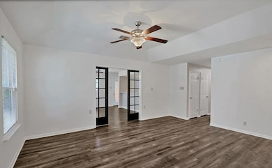 Unfurnished room featuring ceiling fan, dark wood
