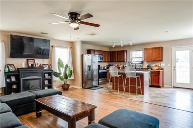 Living area with light wood-style floors, a ceiling fan, and a glass covered fireplace