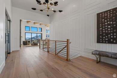 Hallway with an upstairs landing, a mountain view, light wood-type flooring, a chandelier, and a decorative wall