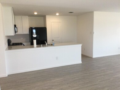 Kitchen featuring refrigerator, a sink, white cabinetry, light countertops, and range.Appliances furnished in this rental.
