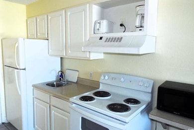 Kitchen with range hood, white cabinetry, sink, an