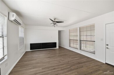 Open floor plan with A/C, floating cabinet, ceiling fan and newly installed wood look flooring.
