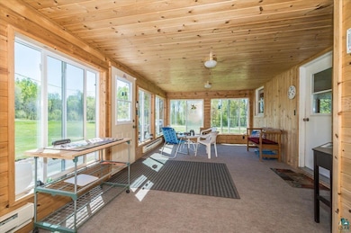 Sunroom with carpet, plenty of natural light, wood ceiling, wooden walls, and baseboard heating