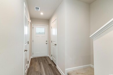 Doorway with wood finished floors, visible vents, 