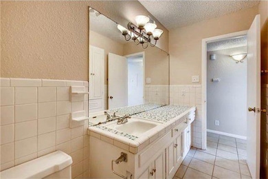 Bathroom with tile walls, vanity, a textured ceil