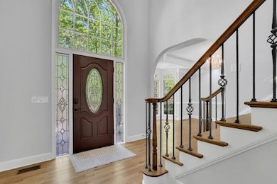 Entrance foyer with a high ceiling, wood finished floors, arched walkways, baseboards, and stairs