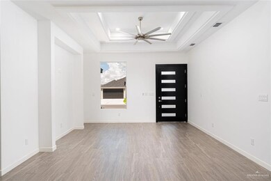Foyer entrance featuring visible vents, a ceiling fan, a tray ceiling, and wood finished floors