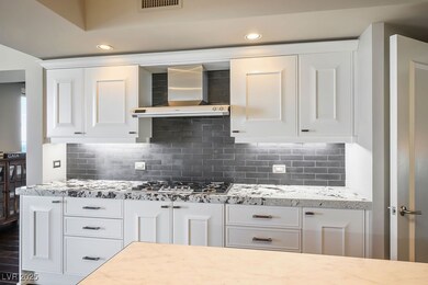 Designer kitchen remodel with stainless cooktop and drop down hood, custom backsplash.