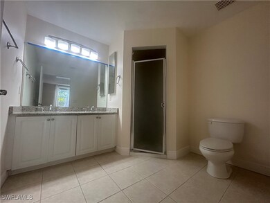 Bathroom with double vanity, a stall shower, and t