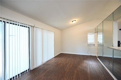 Unfurnished bedroom featuring dark wood finished floors and vaulted ceiling