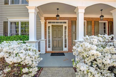 View of exterior entry featuring covered porch and brick siding