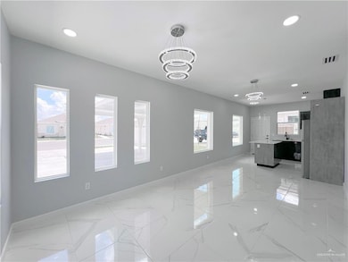 Unfurnished living room featuring a wealth of natural light, a notable chandelier, marble finish floor, and baseboards