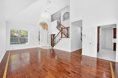 Unfurnished living room featuring stairway, light wood finished floors, high vaulted ceiling, and ceiling fan