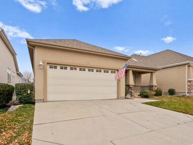 View of front facade featuring stucco siding, roof with shingles, driveway, a porch, and an attached garage