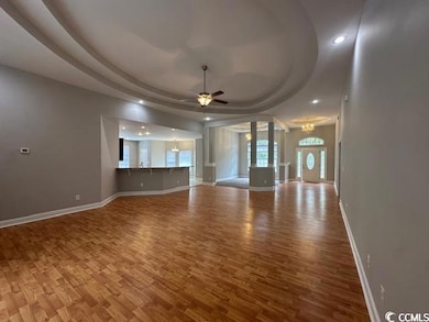 Unfurnished living room featuring a raised ceiling, wood finished floors, recessed lighting, a chandelier, and ceiling fan