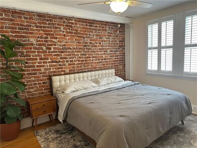 Bedroom featuring brick wall, crown molding, wood finished floors, ceiling fan, and baseboards