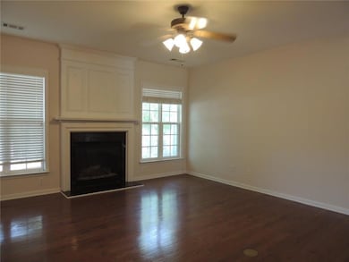 Unfurnished living room featuring ceiling fan, baseboards, dark wood finished floors, and plenty of natural light