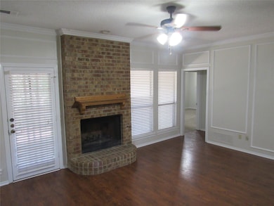 Unfurnished living room with a decorative wall, crown molding, a fireplace, dark wood finished floors, and a textured ceiling