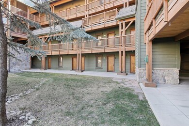 Rear view of house with stone siding, a lawn, and roof with shingles