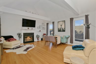 The living room has a vaulted ceiling, beams, and hardwood floors.