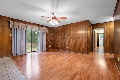 Unfurnished room featuring wood walls, ceiling fan