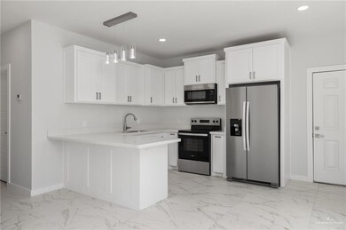 Kitchen featuring sink, kitchen peninsula, stainless steel appliances, pendant lighting, and white cabinets