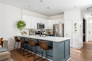 Kitchen featuring appliances with stainless steel finishes, a sink, a peninsula, a breakfast bar area, and recessed lighting