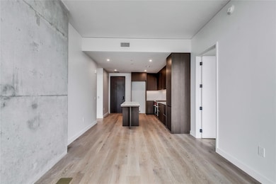 Kitchen featuring a kitchen island, dark brown cabinetry, light wood-style floors, modern cabinets, and recessed lighting