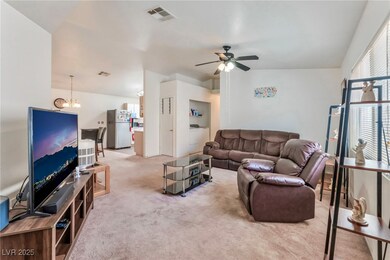 Carpeted living room with ceiling fan, a chandelie