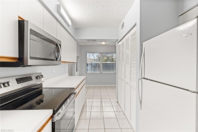Kitchen featuring appliances with stainless steel finishes, light countertops, white cabinetry, and a textured ceiling