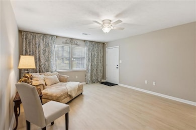 Living area featuring light wood-style floors, a ceiling fan, and a textured ceiling