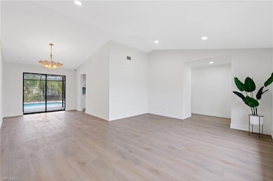 Unfurnished room with a notable chandelier, light wood-style floors, recessed lighting, baseboards, and lofted ceiling