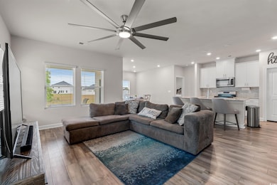 Living area featuring a ceiling fan, baseboards, r
