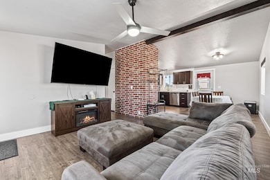 Living area with wood finished floors, ceiling fan, a glass covered fireplace, and a textured ceiling