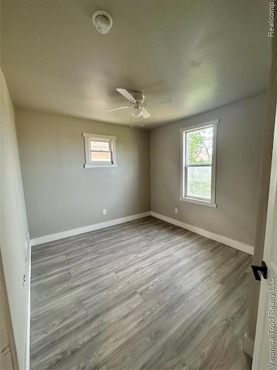 Spare room with light wood-type flooring, healthy amount of natural light, a ceiling fan, and a smoke detector