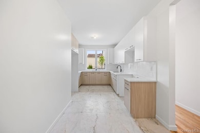 Kitchen with light brown cabinets, light marble finish floors, modern cabinets, decorative backsplash, and white cabinets