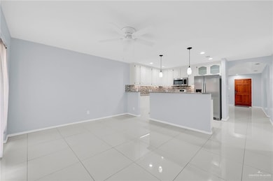 Kitchen featuring stainless steel appliances, arched walkways, backsplash, white cabinetry, and light tile patterned floors