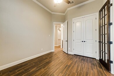 Unfurnished bedroom featuring a closet, visible vents, crown molding, baseboards, and dark wood finished floors