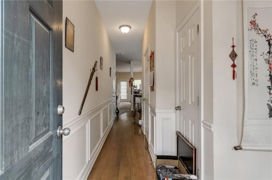 Hallway with wood finished floors, a decorative wall, and wainscoting