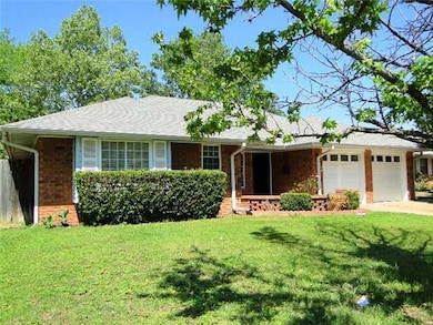 Single story home featuring an attached garage, a front lawn, brick siding, and driveway