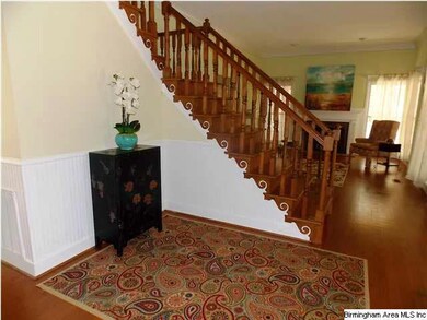 Foyer view looking into formal living room w/ hardwood floors and fireplace, not to mention lots of windows for maximum light filtration.  Tall ceilings accented with moldings and wainscoting add richness.