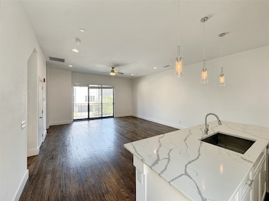 Kitchen featuring a kitchen island with sink, decorative light fixtures, dark wood finished floors, recessed lighting, and light stone countertops