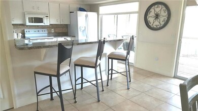 Kitchen with stone backsplash, white appliances, l