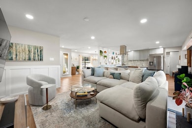 Living area featuring wood finished floors, a wainscoted wall, recessed lighting, a decorative wall, and a chandelier