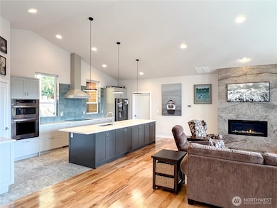 Lovely, large quartz countertop island with lots of cabinet storage and a small eating bar at the near end.