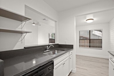 Kitchen featuring a sink, open shelves, dark coun