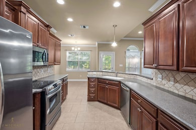 Kitchen featuring tasteful backsplash, stainless steel appliances, crown molding, recessed lighting, and a chandelier