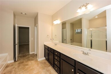 Bathroom featuring a bath, double vanity, and baseboards
