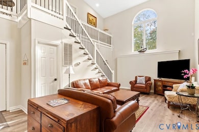 Living room with light wood-style floors, stairs, and a towering ceiling